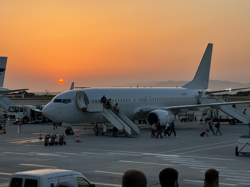 A photo of the sun setting over an airplane on the tarmac
